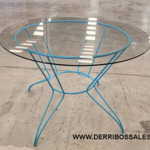 Mesa con pies de hierro y tapa de cristal.