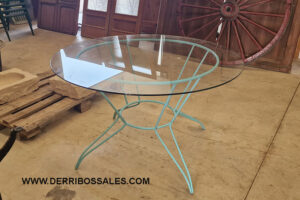 Mesa con pies de hierro y tapa de cristal.